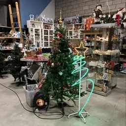 Winkelbinnenruimte met kerstdecoratie, groene neonlichtboom, glas vitrines en diverse uitgestalde spullen