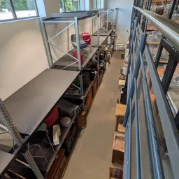 Smalle gang tussen stellingen met werkruimte en opslag in kringloopwinkel