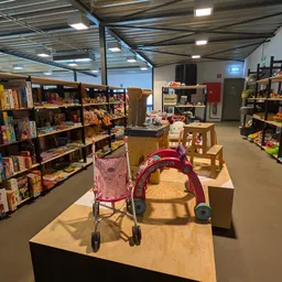 Winkelinterieur met boekenrekken, speelgoed en kinderwagens op houten platforms
