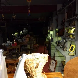 Interieur van kringloopwinkel met verlichte display-kasten, houten meubels en diverse spullen in de nachtverlichting