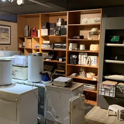 Winkelinterieur met houten kasten, wasmachines, drogers en diverse huishoudelijke artikelen op stellingen