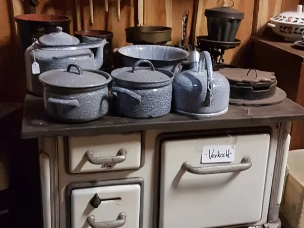 Granieten kookpotten en ketel op een vintage fornuis in een antiekwinkel