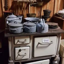 Granieten kookpotten en ketel op een vintage fornuis in een antiekwinkel