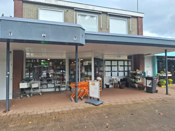 Winkelgevel met grote ramen, ingang en terrasoverkapping, met enkele spullen buiten uitgestald