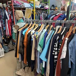 Rekken met tweedehands kleding op houten hangers, met diverse kleuren en patronen