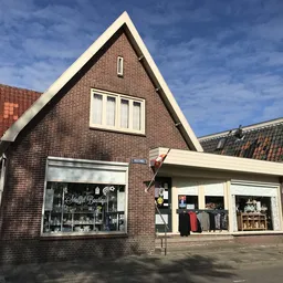 Bakstenen winkelpui met twee etalages en gevel van kringloopwinkel aan straatzijde