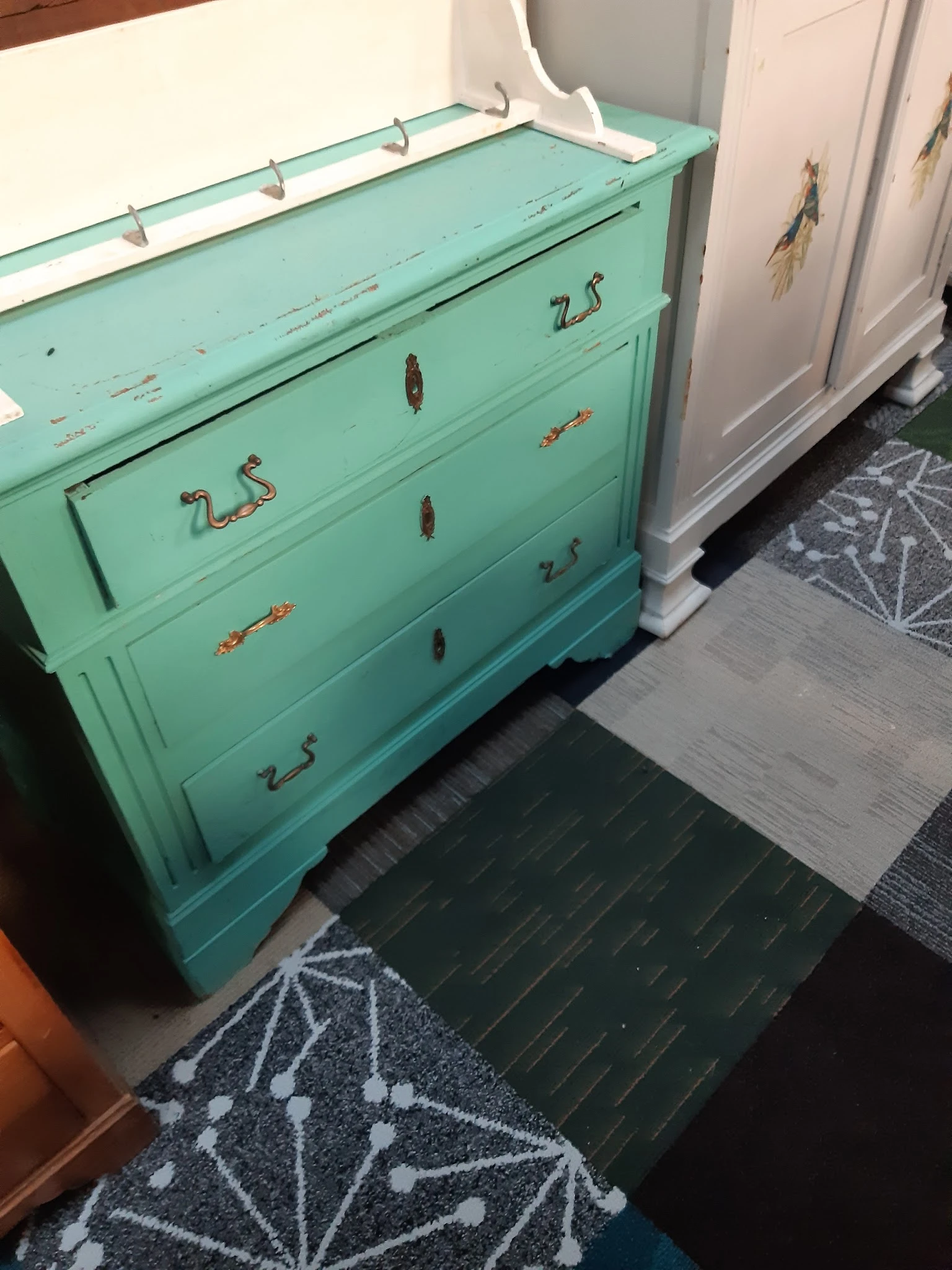 Turquoise commode met vier laden en koperen handles, zijkant gefotografeerd