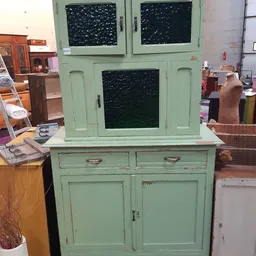 Groen geschilderd vintage kastje met glazen deuren bovenin en twee lades en kastdeuren onderin