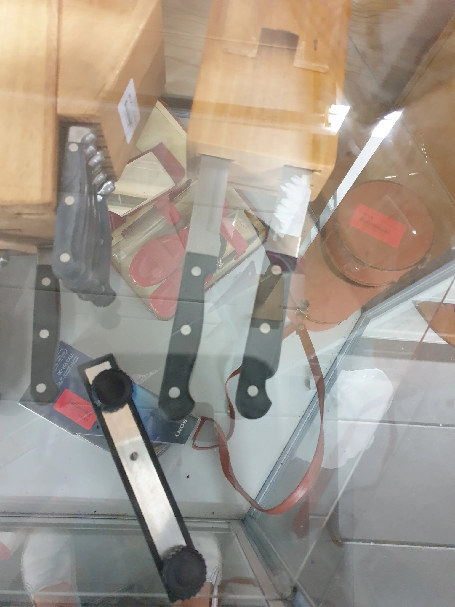 Diverse keukenmessen met zwarte handvatten in een messenblok, met andere huishoudartikelen op de achtergrond