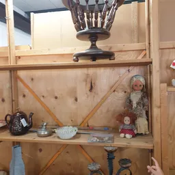 Houten stellingkast met vintage huishoudartikelen, decoraties en poppenhuispoppen