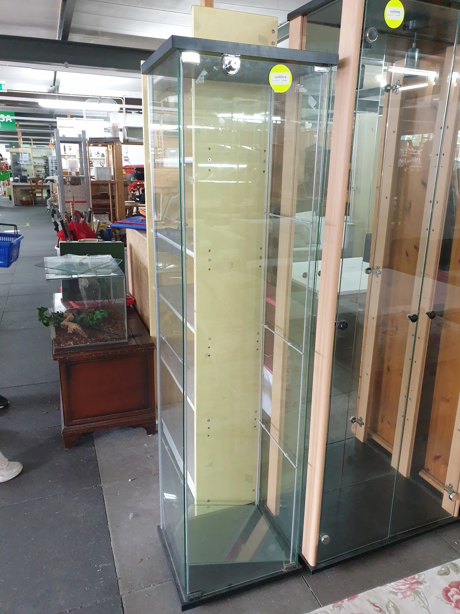 Glazen displaykasten en vitrines langs de winkelvloer van een kringloopwinkel