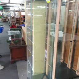 Glazen displaykasten en vitrines langs de winkelvloer van een kringloopwinkel