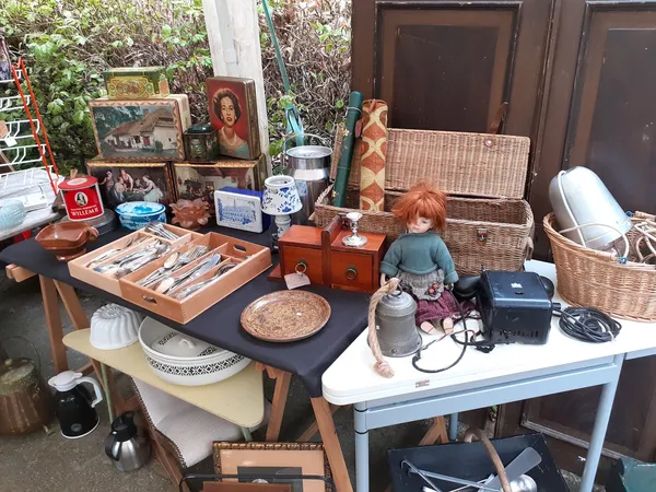 Uitgestalde tweedehands spullen op tafels: meubels, bestek, servies, siervoorwerpen, textiel en decoratieve items