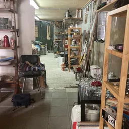 Smalle winkelgang met stellingen, dozen en diverse spullen langs de zijkanten