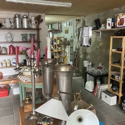 Binnenaanzicht van kringloopwinkel met stellingen, huishoudelijke artikelen, keukengerei en diverse spullen