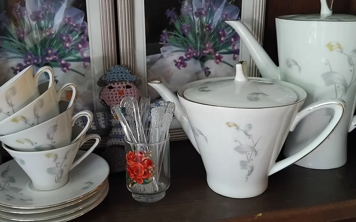 Uitgestalde serviesgoed: kopjes, schotels, theepot en kitchenware op een donkere tafel