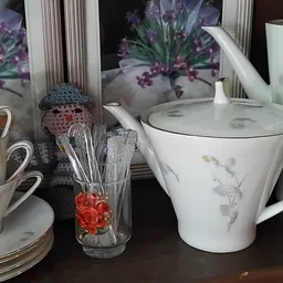 Uitgestalde serviesgoed: kopjes, schotels, theepot en kitchenware op een donkere tafel