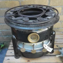 Zwarte vintage kachel of fornuis met messing onderdelen en regelknoppen