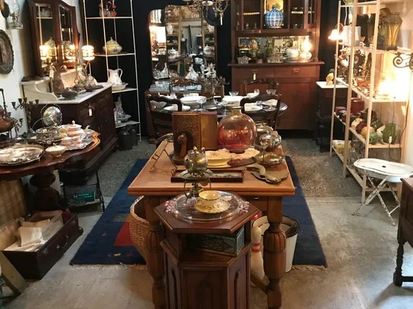 Winkelvloer van kringloopwinkel met houten meubels, vitrines, kasten en decoratieve artikelen langs de wanden
