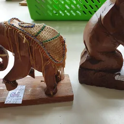 Houten beeldje van een olifant met decoratieve stoffen doek, op houten voet