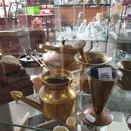 Gouden koperen kookgerei in een vitrinekasten, inclusief pannen, kannen en keukengereedschap