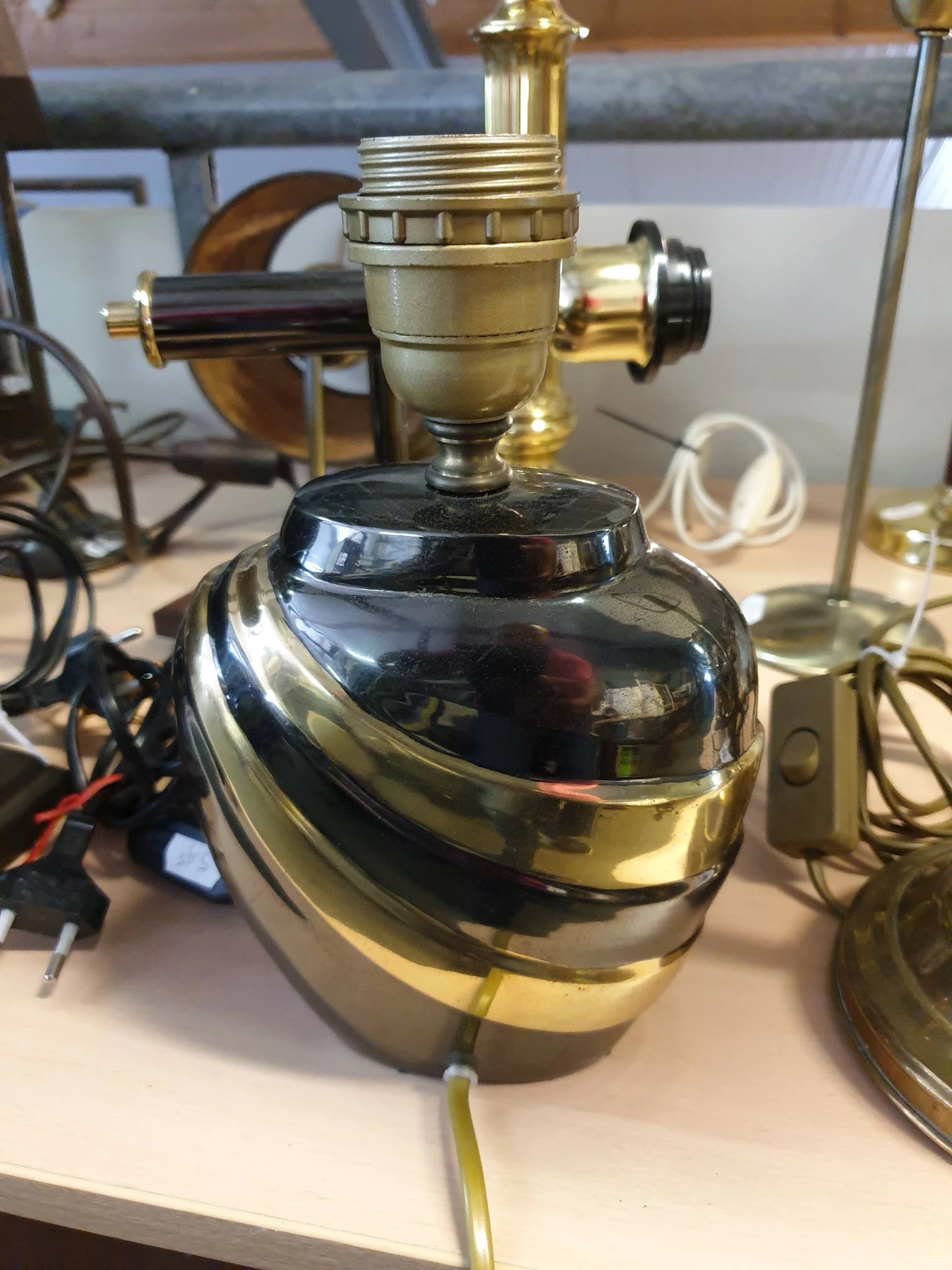 Zwart glimmende tafellamp met messing accenten en stoffen kap, close-up.