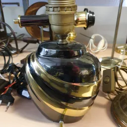 Zwart glimmende tafellamp met messing accenten en stoffen kap, close-up.