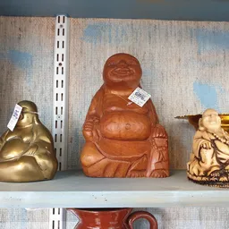 Drie decoratieve boeddhabeelden in verschillende materialen en kleuren op een plank