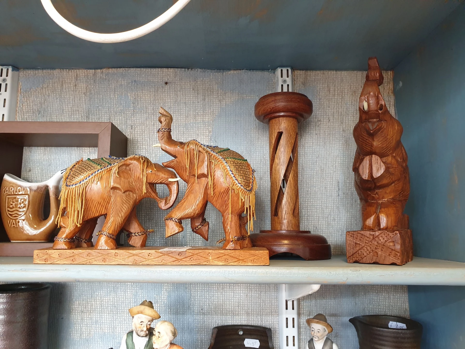 Houten beeldjes en decoratieve items op een plank: olifanten, standbeelden en houtsculpturen