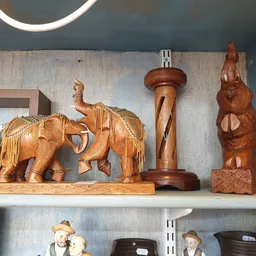 Houten beeldjes en decoratieve items op een plank: olifanten, standbeelden en houtsculpturen