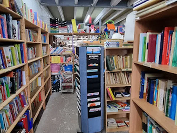 Boekenkasten met tweedehands boeken langs de wanden in een kringloopwinkel, met een centrale stellage in het midden