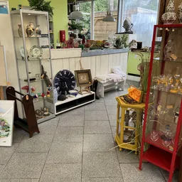Winkelinterieur met vitrines, een grote klok, gele stellage en diverse decoratieve spullen op tafels en in kasten