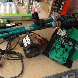 Groene elektrische grasmaaier met accessoires en onderdelen op een werkblad