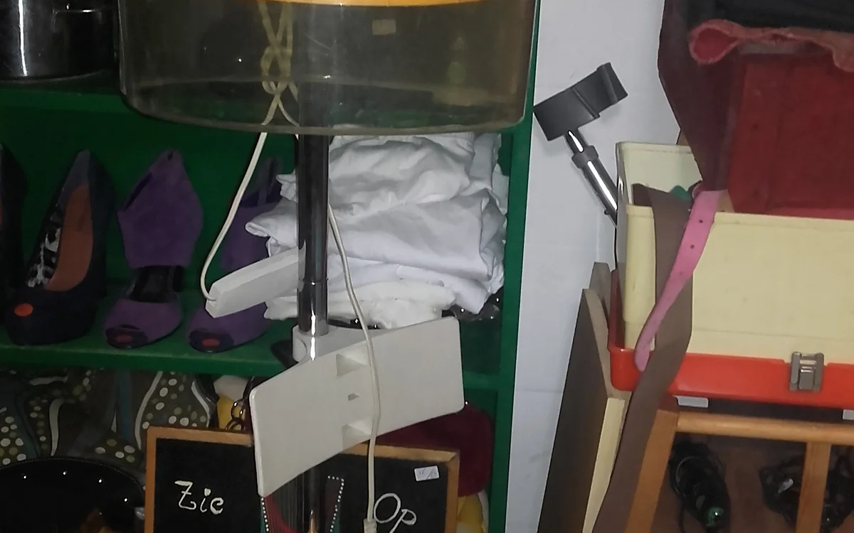 Verzameling van tweedehands huishoudartikelen en textiel op planken en dozen in een kringloopwinkel