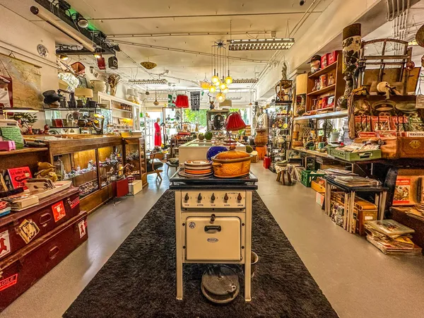 Winkelvloer van een kringloopwinkel met vintage items, kasten, servies en decoratieve spullen aan beide zijden