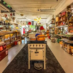 Winkelvloer van een kringloopwinkel met vintage items, kasten, servies en decoratieve spullen aan beide zijden