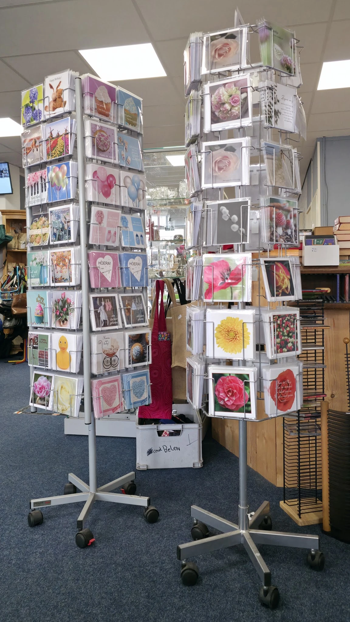 Draaiende displaystandaards met uitgestalde wenskaarten, ansichtkaarten en bloemenafbeeldingen in de winkel