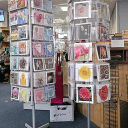 Draaiende displaystandaards met uitgestalde wenskaarten, ansichtkaarten en bloemenafbeeldingen in de winkel