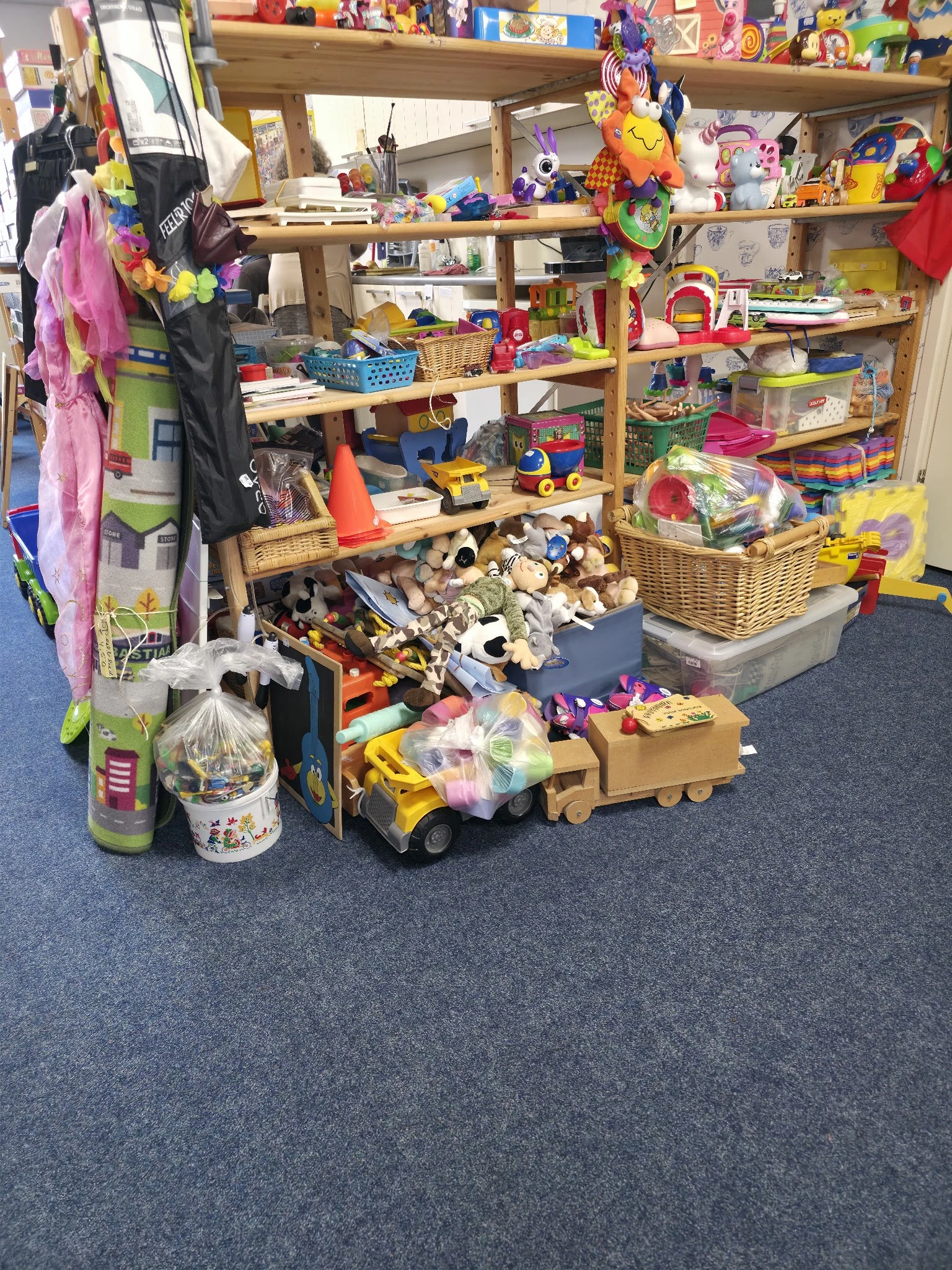 Diverse speelgoed en kinderartikelen op de vloer en in bakken in de kringloopwinkel