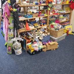 Diverse speelgoed en kinderartikelen op de vloer en in bakken in de kringloopwinkel