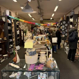 Winkelinterieur met stellingen, uitgestalde spullen en bezoekers; regenboogslinger aan plafond