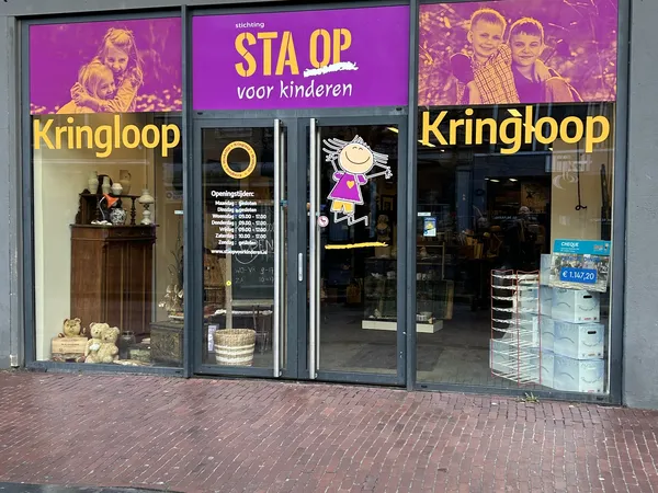 Winkelfront met paarse en gele etalage, winkelnaam Kringloop zichtbaar, grote ramen met uitstallingen