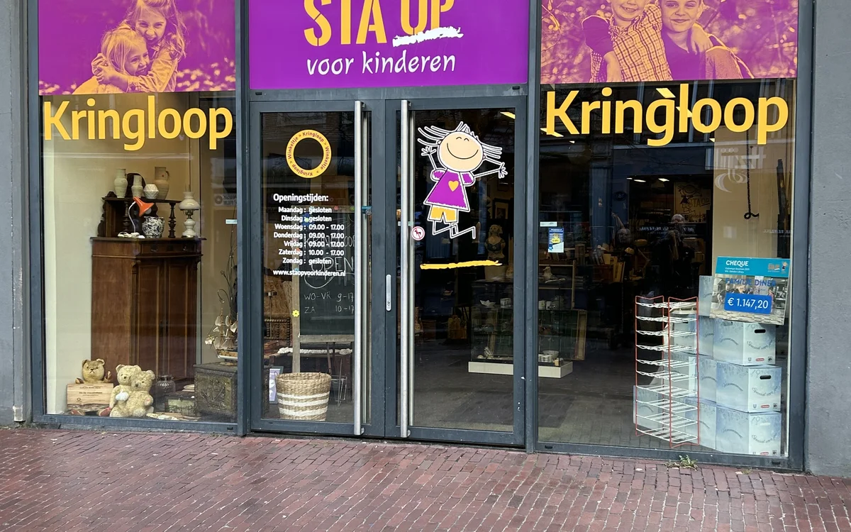 Winkelfront met paarse en gele etalage, winkelnaam Kringloop zichtbaar, grote ramen met uitstallingen