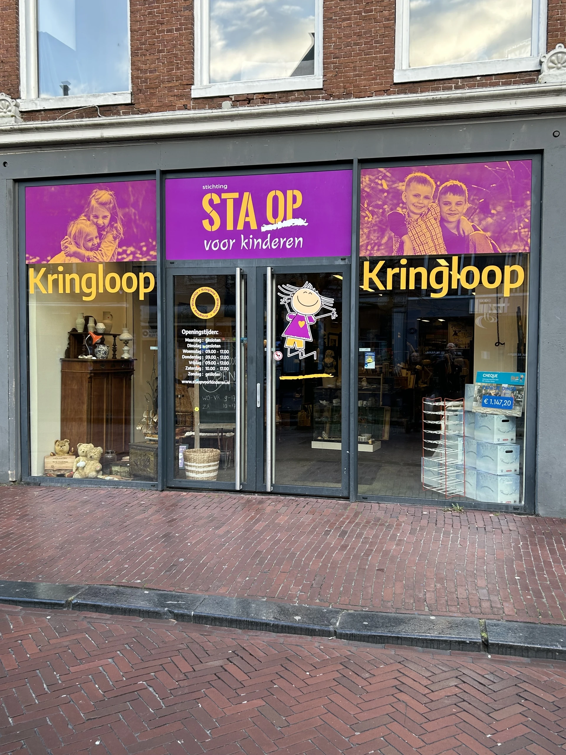 Winkelfront met paarse en gele etalage, winkelnaam Kringloop zichtbaar, grote ramen met uitstallingen