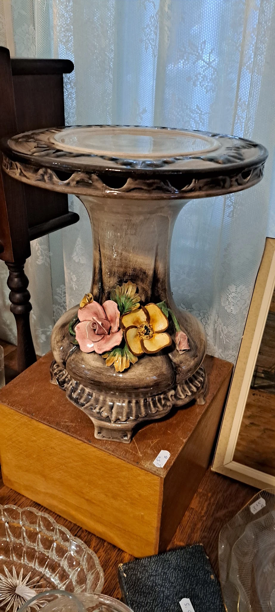 Decoratieve schaal met sculpturen van roze en gele bloemen, onder een glazen stolp