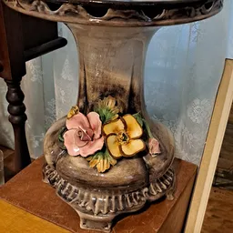 Decoratieve schaal met sculpturen van roze en gele bloemen, onder een glazen stolp
