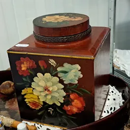 Houten juwelenkistje met bloemendecoratief werk en ronde sieradendoos erop