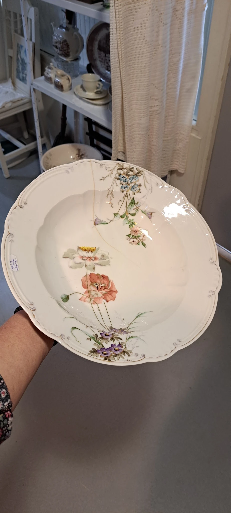 Decoratief porseleinen bord met bloemmotief, wordt in hand gehouden
