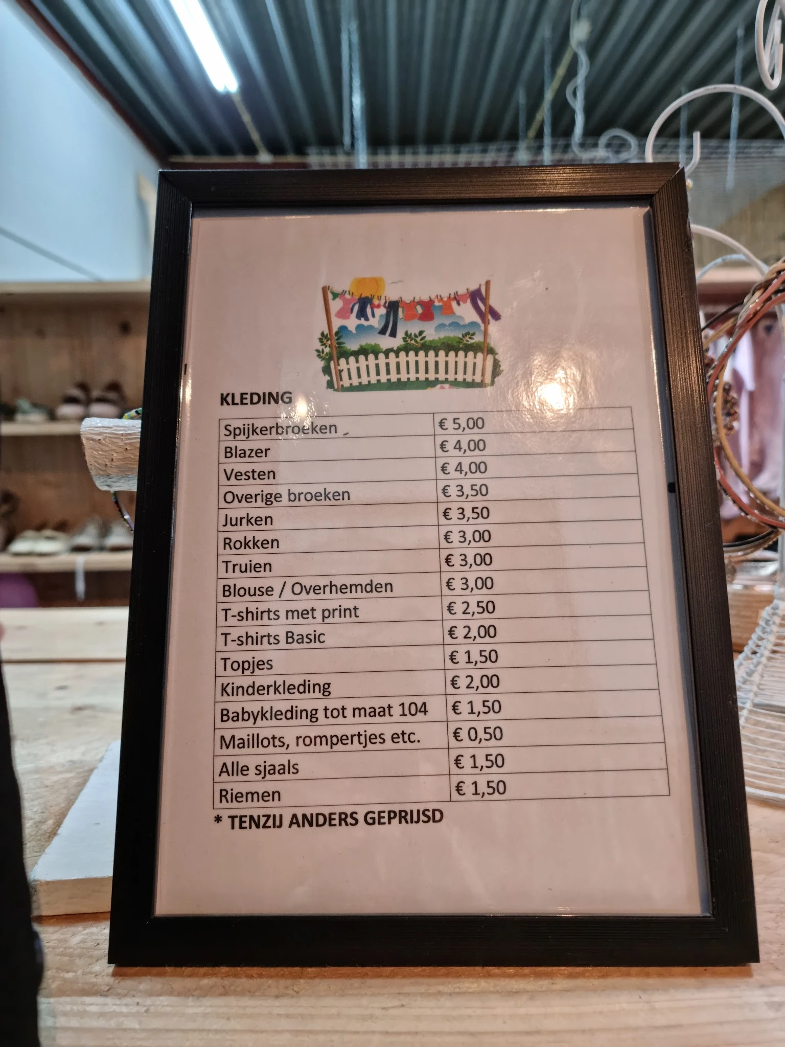 Prijsbord met aanbod kleding en items in een kringloopwinkel, prijzen van €0,50 tot €5,00