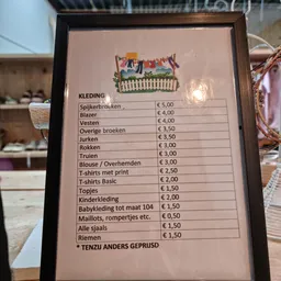 Prijsbord met aanbod kleding en items in een kringloopwinkel, prijzen van €0,50 tot €5,00